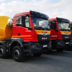 Rzędy czerwonych gruszek betonu MAN LUBAR. Zastanawiasz się, ile kosztuje gruszka betonu? Te potężne maszyny budowlane są gotowe do pracy.