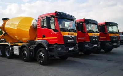 Rzędy czerwonych gruszek betonu MAN LUBAR. Zastanawiasz się, ile kosztuje gruszka betonu? Te potężne maszyny budowlane są gotowe do pracy.