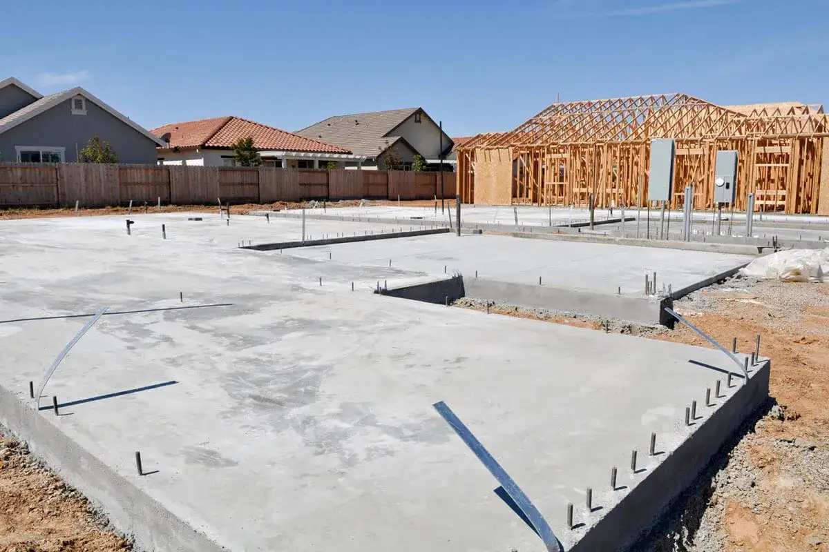 Fundament domu w budowie, z widocznym betonem i zbrojeniem. Odpowiednie kruszywo do betonu jest kluczowe dla trwałości tej konstrukcji.